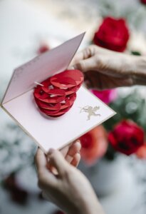 Faceless woman opening pop up gift card with decorative heart